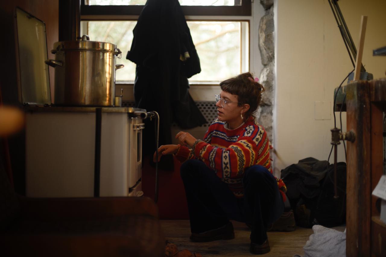 Theresa in her cozy Italian studio, tending to a traditional stove as part of her natural dyeing process for Cocou accessories.