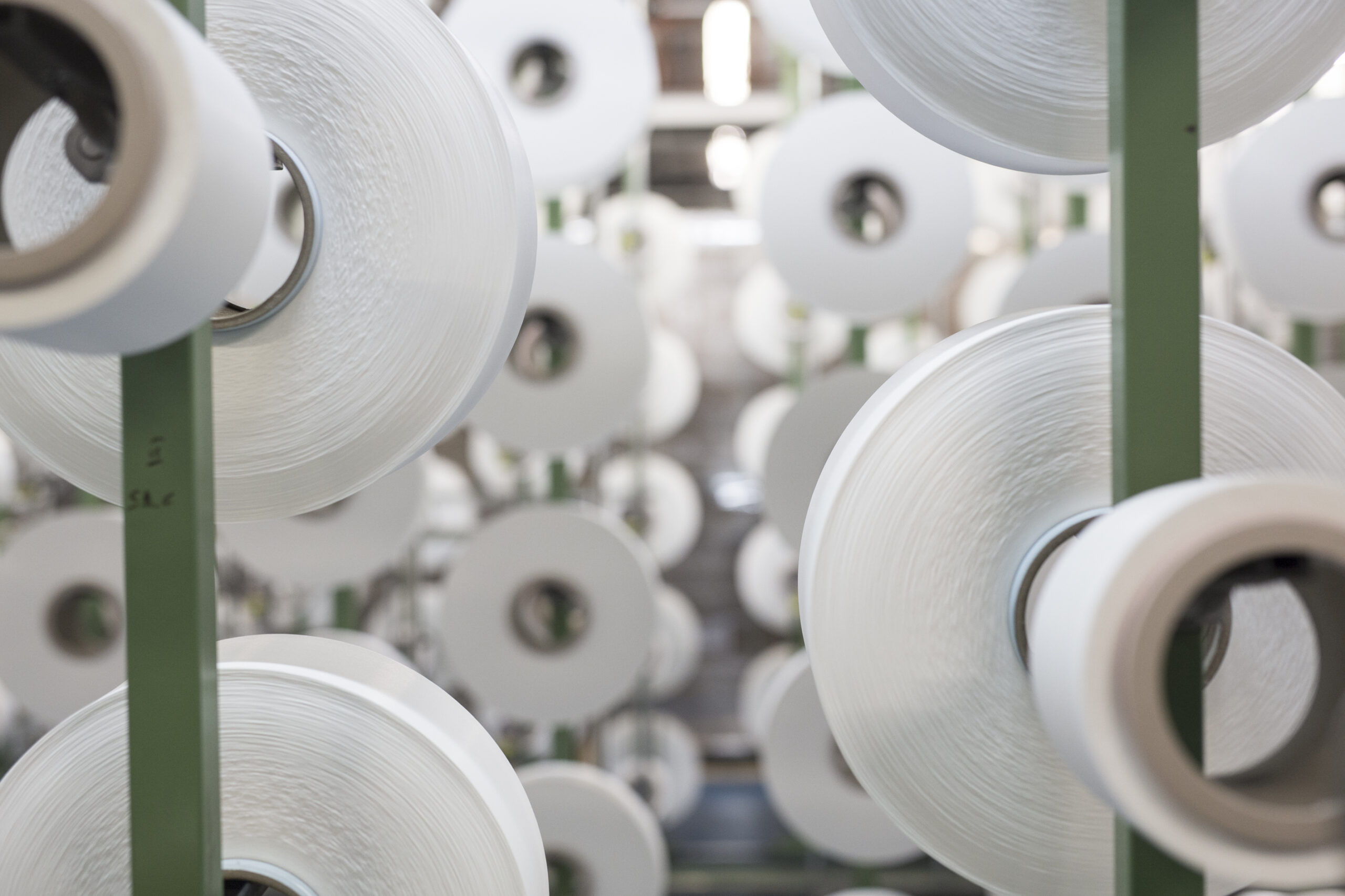 ECONYL® yarn spools – sustainable regenerated nylon threads made from recycled fishing nets and nylon waste, ready for eco-friendly swimwear production.