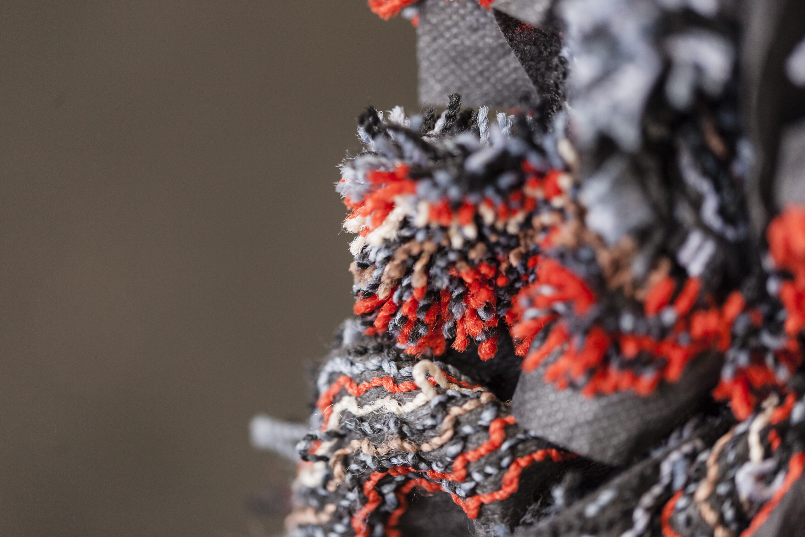 Close-up view of recycled carpet fibers used in the production of ECONYL® regenerated nylon, showcasing a mix of red, black, and neutral tones.