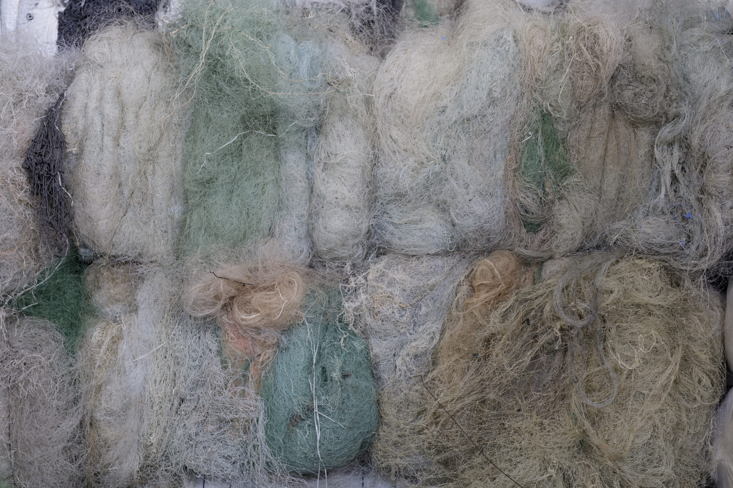 Bundles of discarded ghost fishing nets in muted greens and beige tones, later recycled into ECONYL® fabric for COCOU’s sustainable swimwear.