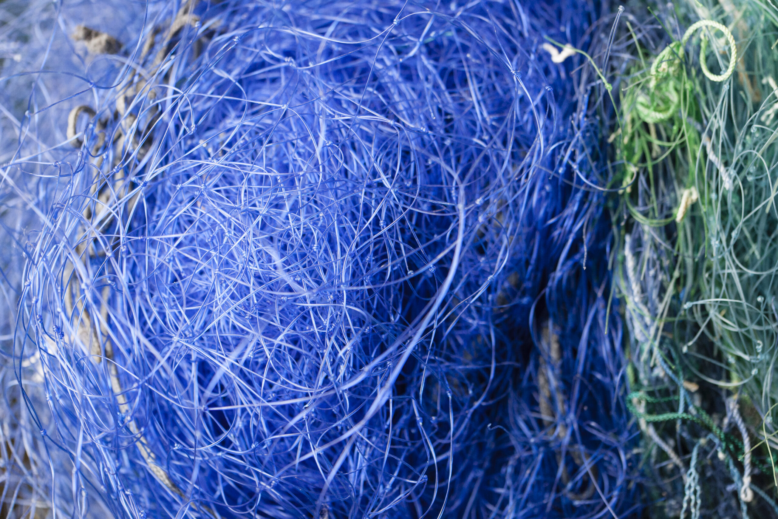 Close-up of discarded blue and green fishing nets, symbolizing ocean pollution and the raw material used in COCOU’s sustainable swimwear made from ECONYL® regenerated nylon.