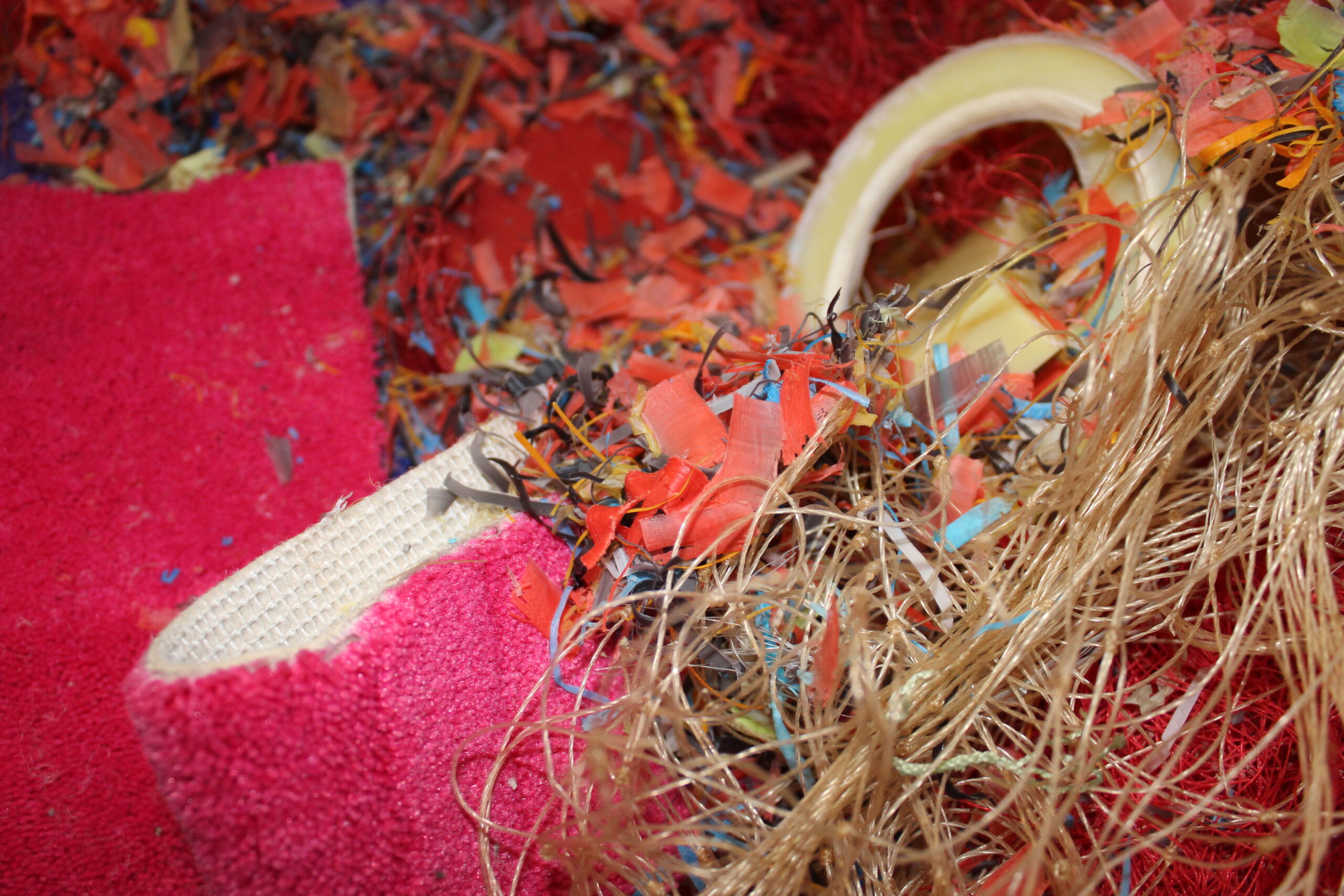 Close-up view of recycled carpet fibers used in the production of ECONYL® regenerated nylon, showcasing a mix of red, black, and neutral tones.