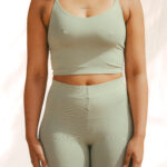 Model wearing the pale olive-green COCOU Alare strappy crop top with matching pants.